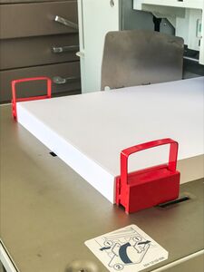 A pair of red-handled magnets securing the back of a stack of letter-sized paper.